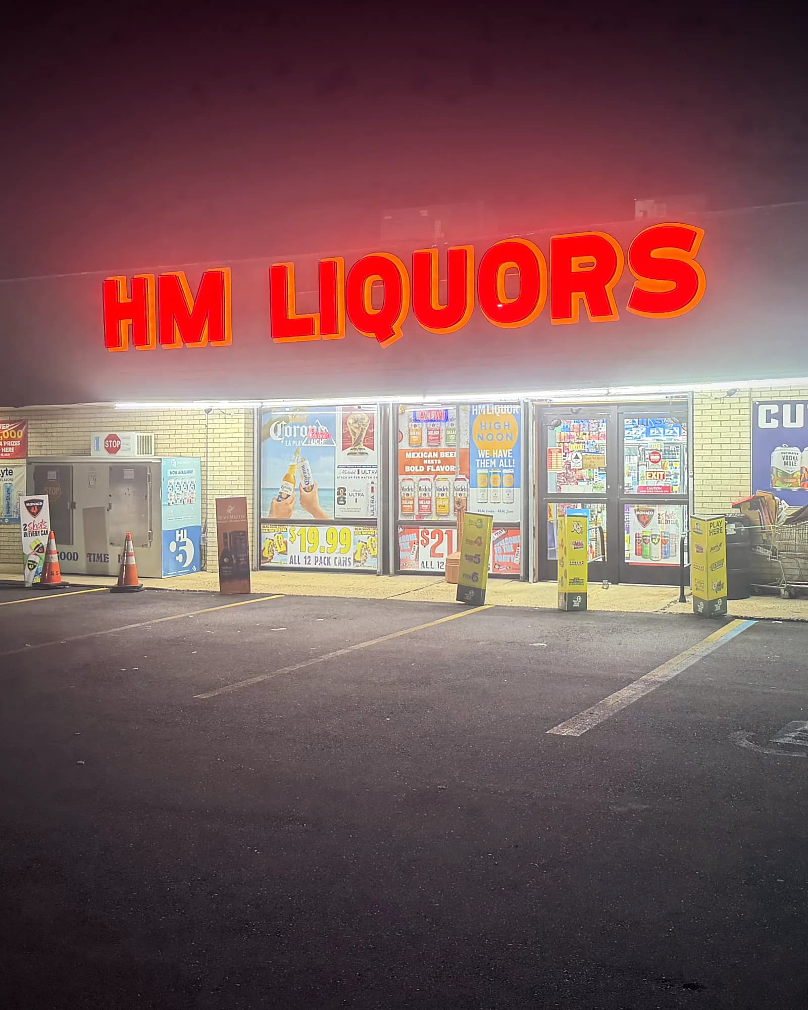 The HM Liquors storefront at night, its red sign lit above the front doors on US-130